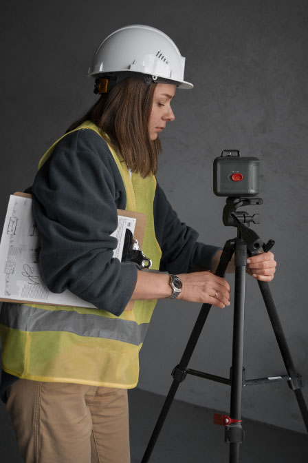 Survey technician operating laser scanning tripod inside commercial building